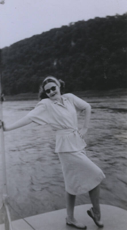Untitled [Woman stands on boat deck, hand on hip]