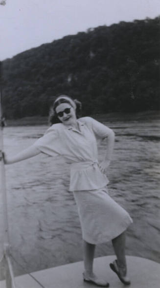 Untitled [Woman stands on boat deck, hand on hip]