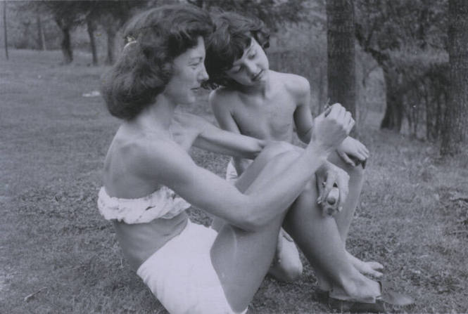 Untitled [Woman and child sit on garden, woman shows child a flower]