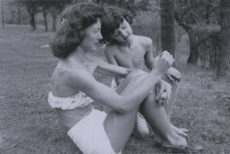 Untitled [Woman and child sit on garden, woman shows child a flower]