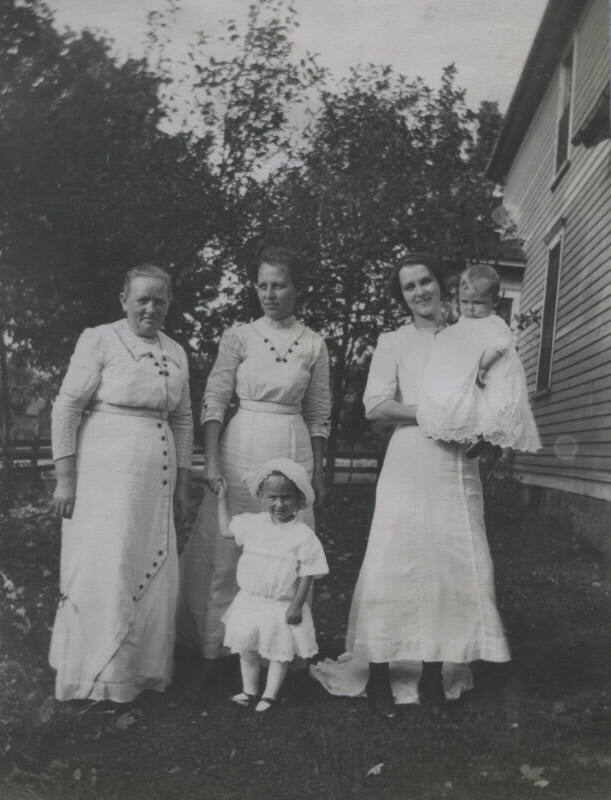 Untitled [Three women stand on lawn with two children]