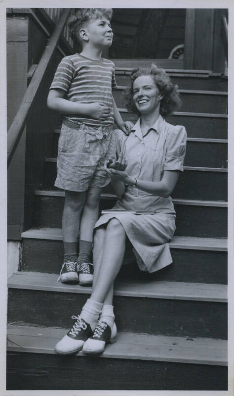 Untitled [Woman sits on porch steps, child by her side]