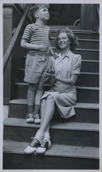 Untitled [Woman sits on porch steps, child by her side]