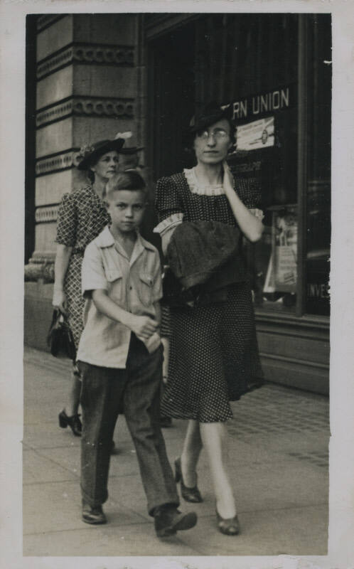 Untitled [Woman and child walk down street, window that reads Western Union in background]