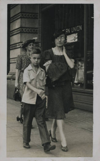 Untitled [Woman and child walk down street, window that reads Western Union in background]
