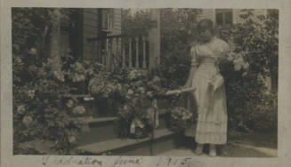 Untitled [Woman stands on porch, holds flowers]