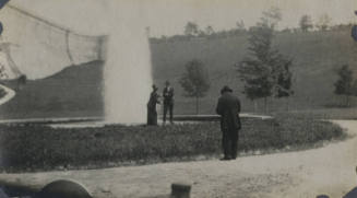 Untitled [Woman and man stand in front of fountain, in the foreground, a man stands]