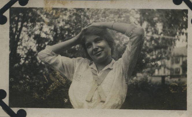 Untitled [Woman stands in garden, rests hands on head, looks out (#5 duplicate)]