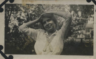 Untitled [Woman stands in garden, rests hands on head, looks out (#5 duplicate)]