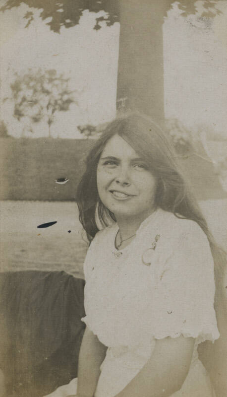 Untitled [Woman sits, body of water in background]