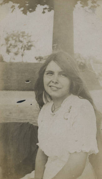 Untitled [Woman sits, body of water in background]
