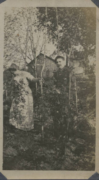 Untitled [Woman and man stand among trees]
