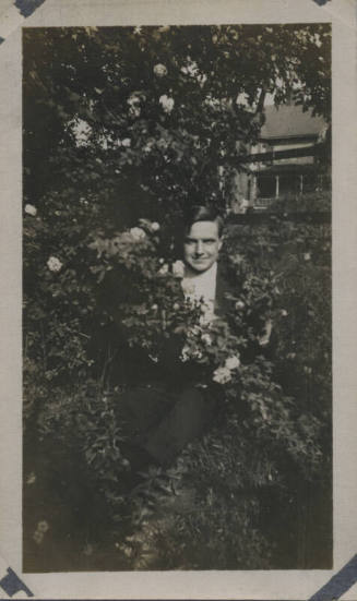 Untitled [Man sits in rosebush]