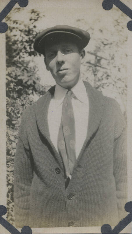 Untitled [Man wears knit sweater, tie, and hat]