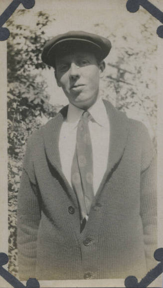 Untitled [Man wears knit sweater, tie, and hat]