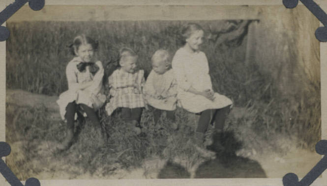 Untitled [Four children sit on log]