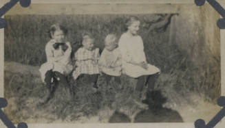 Untitled [Four children sit on log]