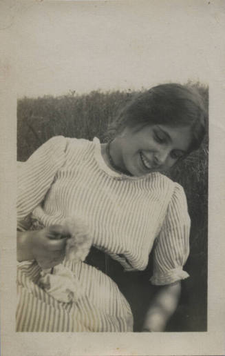 Untitled [Woman stands on field, holds flower]
