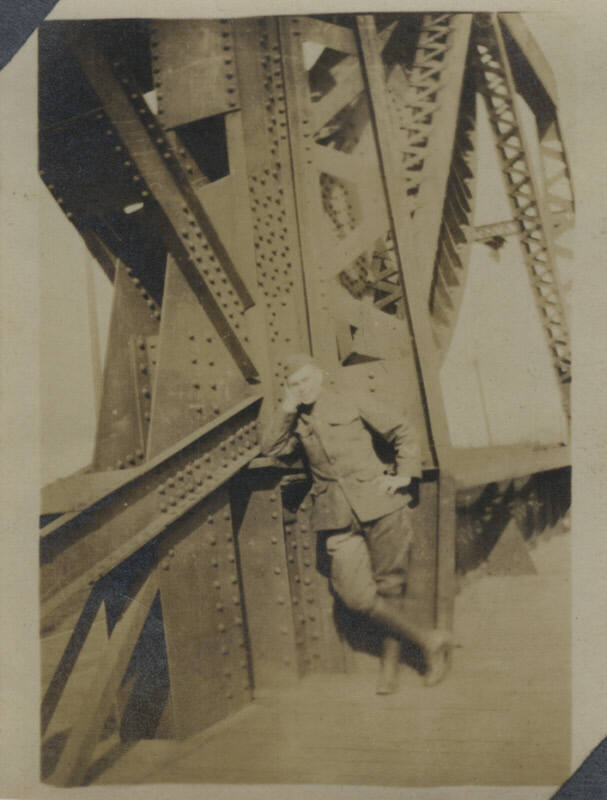 Untitled [Man in uniform leans on bridge]