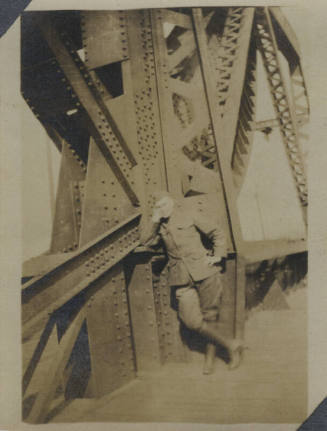 Untitled [Man in uniform leans on bridge]