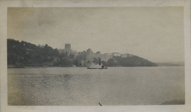 Untitled [Body of water, ship, and buildings in the distance]