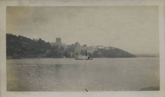 Untitled [Body of water, ship, and buildings in the distance]