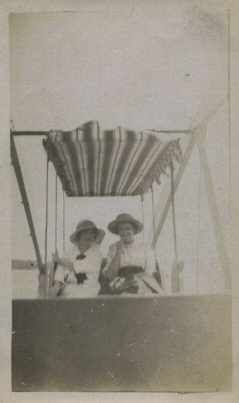 Untitled [Two women sit on ferris wheel cart]