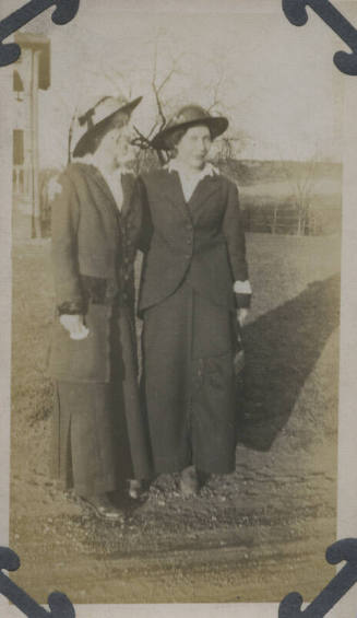 Untitled [Two women stand on lawn, arms around each other's shoulders]
