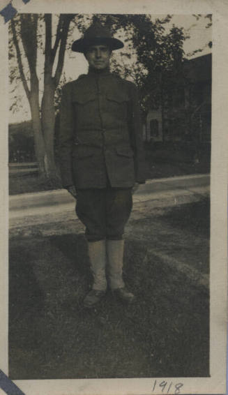 Untitled [Man in uniform stands in lawn]