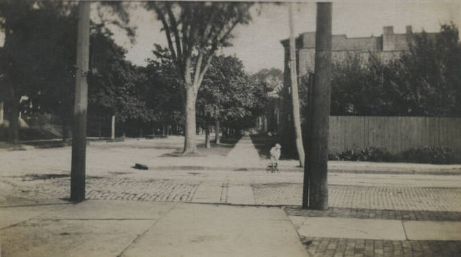 Untitled [Boy pulls cart on street]