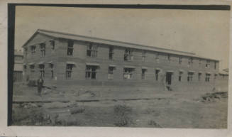 Untitled [Man stands in front of building]