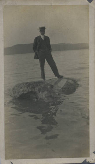 Untitled [Man stands on rock in middle of body of water]