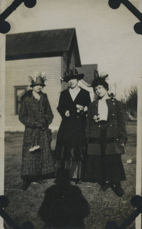 Untitled [Three women stand on lawn, house in background, shadow on floor]