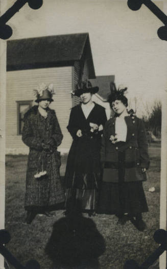 Untitled [Three women stand on lawn, house in background, shadow on floor]