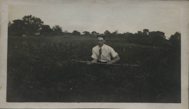 Untitled [Man sits on field, holds bar horizontally]
