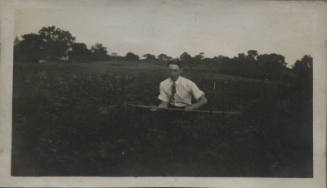 Untitled [Man sits on field, holds bar horizontally]
