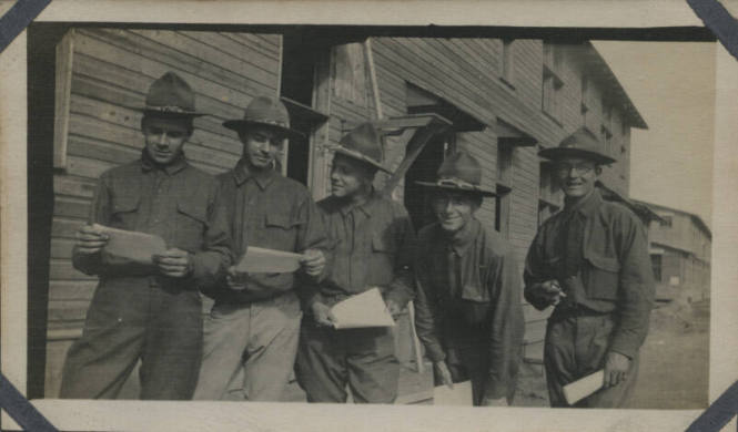Untitled [Five men stand together, wear uniforms, hold paper in hand]