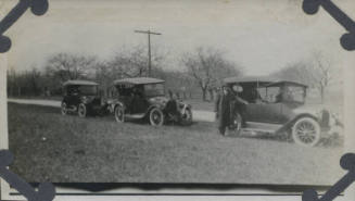 Untitled [Three parked cars, man stands in front of front car]