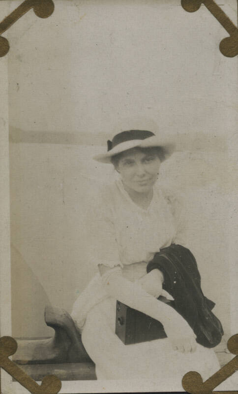 Untitled [Woman sits, wears hat and gloves]