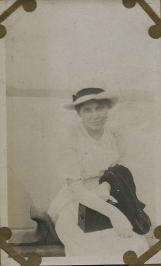 Untitled [Woman sits, wears hat and gloves]