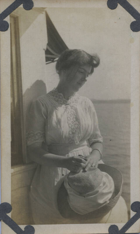 Untitled [Woman stands, holds hat in hands, looks down]