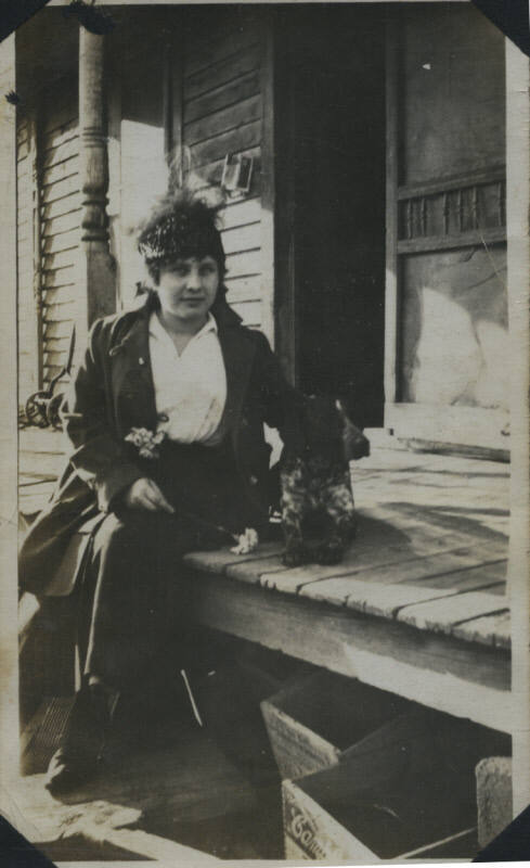Untitled [Woman sits on porch, dog by her side]