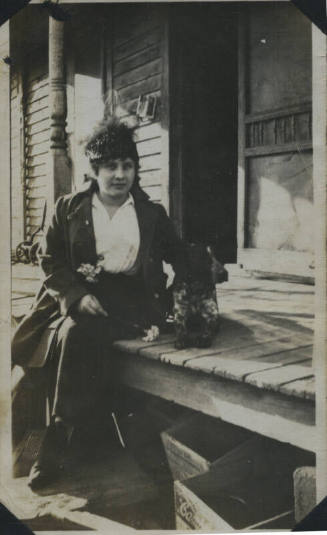 Untitled [Woman sits on porch, dog by her side]