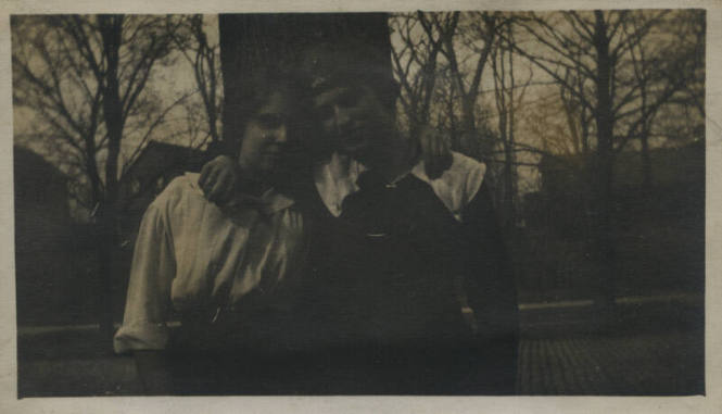 Untitled [Woman and man stand in front of trees, arms around each other's shoulders]