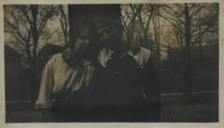 Untitled [Woman and man stand in front of trees, arms around each other's shoulders]