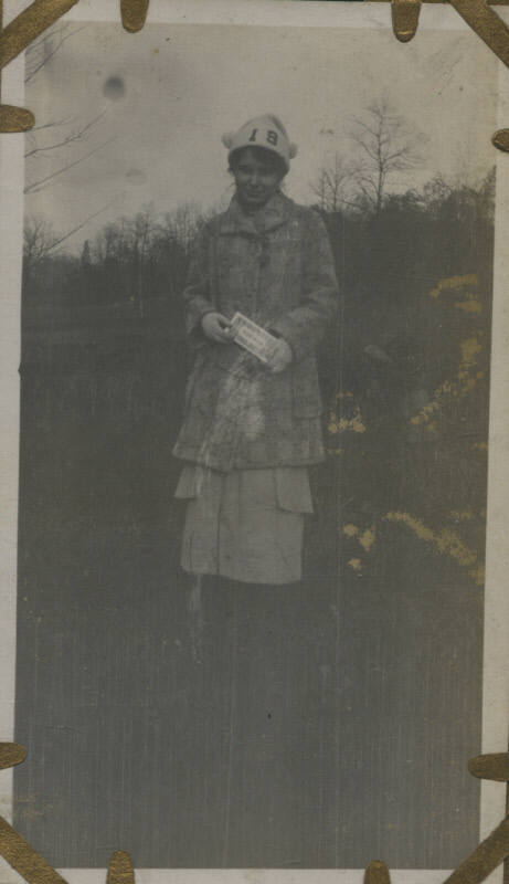 Untitled [Woman stands on field, wears hat that reads 19]