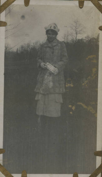Untitled [Woman stands on field, wears hat that reads 19]