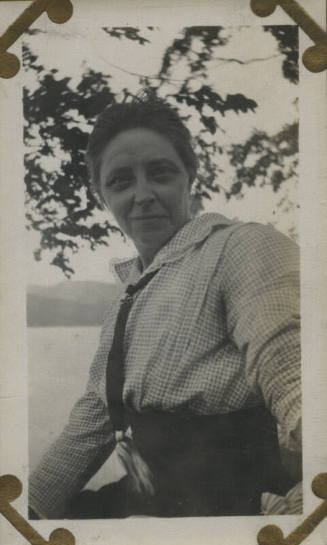 Untitled [Woman sits, body of water in background]