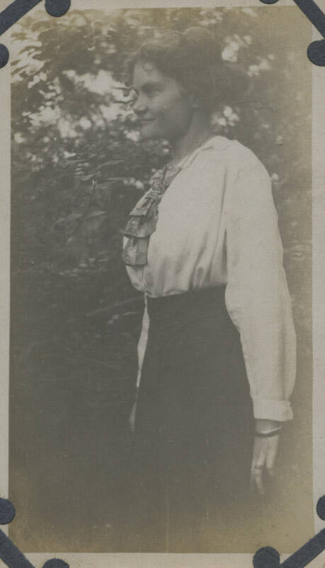 Untitled [Woman stands in garden, faces away]