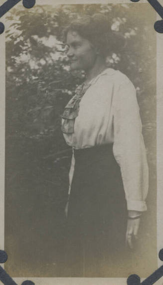 Untitled [Woman stands in garden, faces away]
